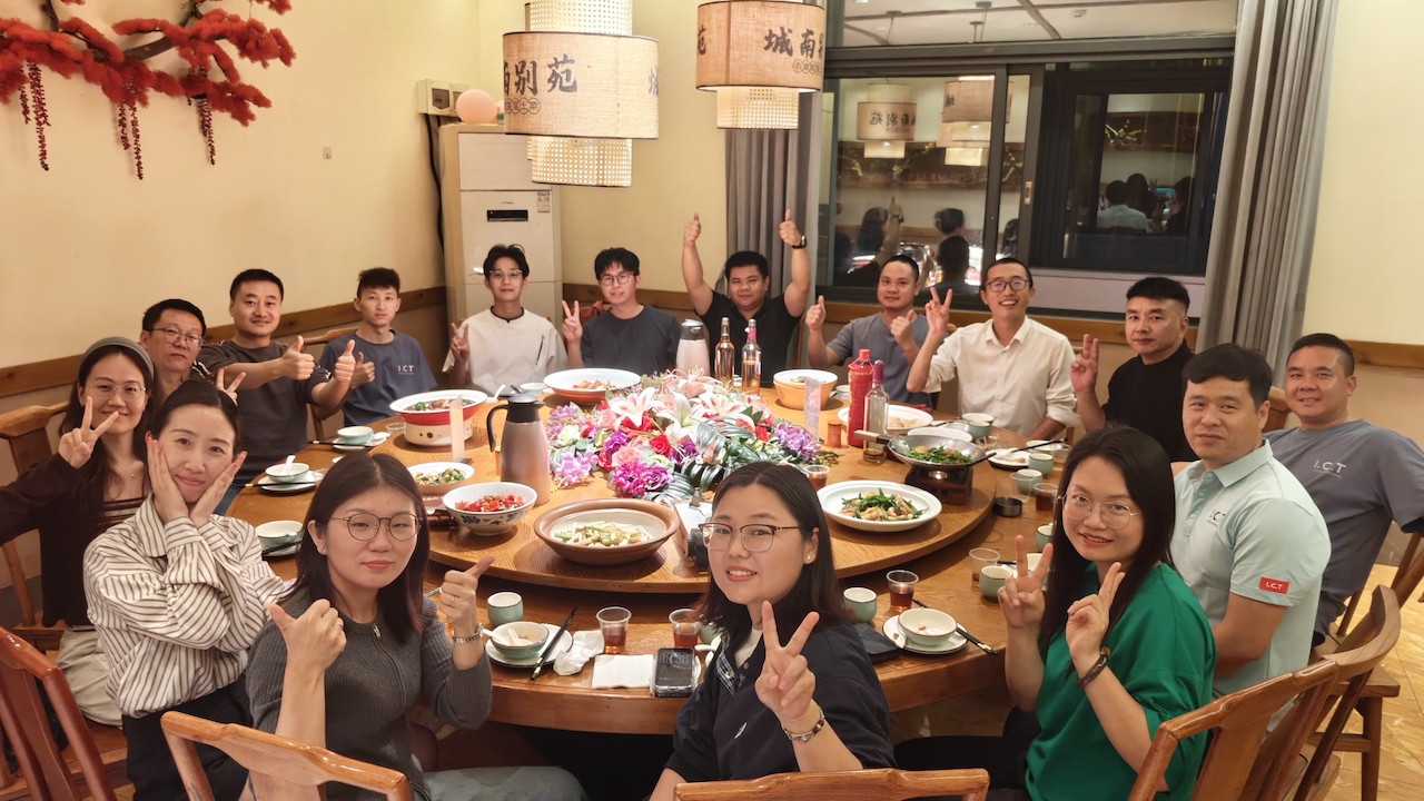 A group photo of I.C.T team members enjoying a celebratory dinner, with smiles and peace signs, marking the addition of four new partners to the company. Uma foto de grupo de membros da equipe I.C.T desfrutando de um jantar comemorativo, com sorrisos e sinais de paz, marcando a adição de quatro novos sócios à empresa.